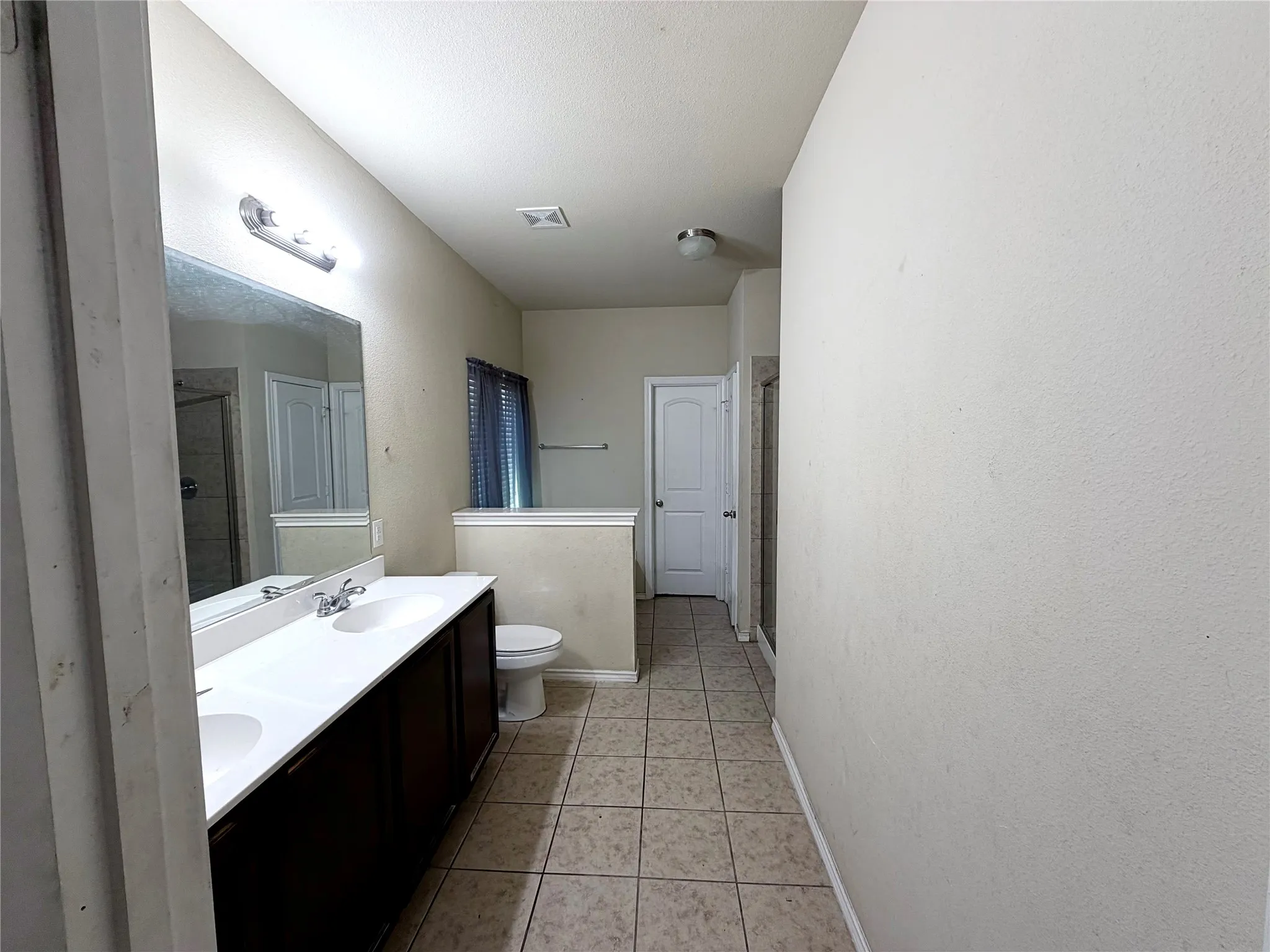 Bathroom featuring a dual vanity with a white countertop and integrated sinks, dark wood-finish cabinetry, and a large mirror