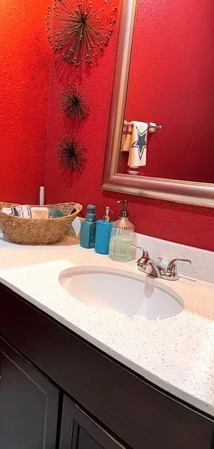 Bathroom vanity with an integrated oval sink, white speckled countertop, and chrome faucet