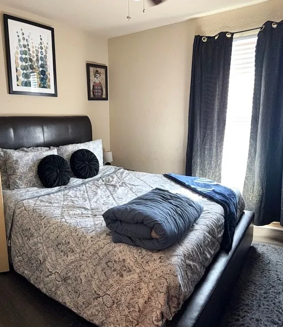 Bedroom featuring wood-finish flooring, a ceiling fan, and a window with blinds