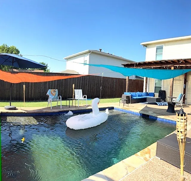 In-ground swimming pool with flagstone coping, surrounding concrete patio, and pergola