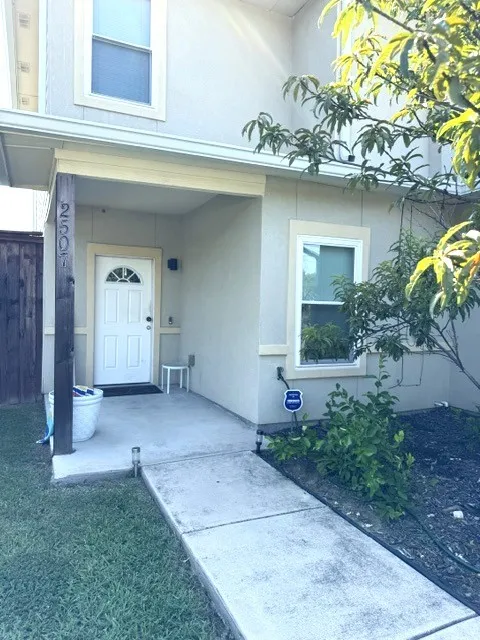 Stucco exterior with a covered front entry featuring a white paneled door with an arched glass insert