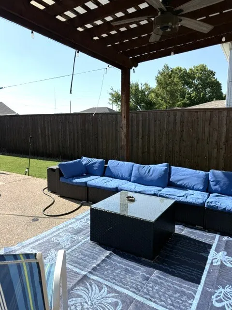 Outdoor pergola featuring a ceiling fan, string lighting, and a stained wood finish