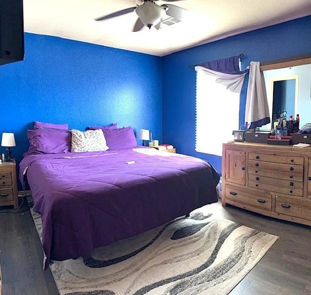 Bedroom featuring wood-finish flooring and textured blue walls