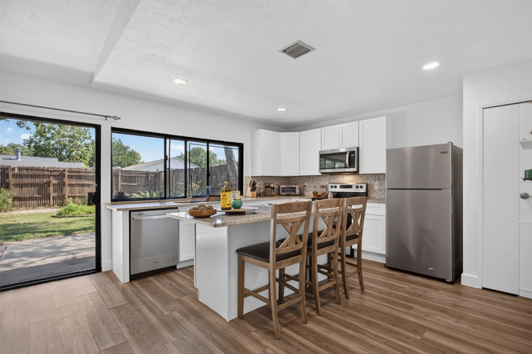 Contemporary kitchen featuring white cabinetry, stainless steel appliances, and a mosaic tile backsplash