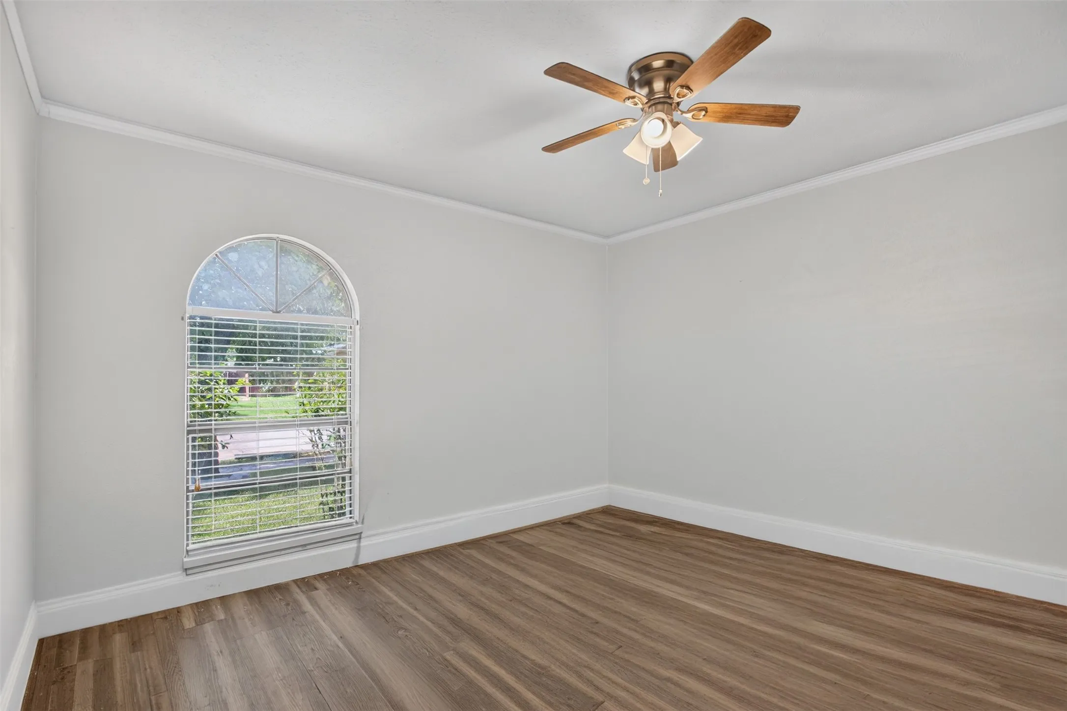 Middle BedRoom featuring wood-finish flooring, white baseboards, crown molding, and an arched window with blinds
