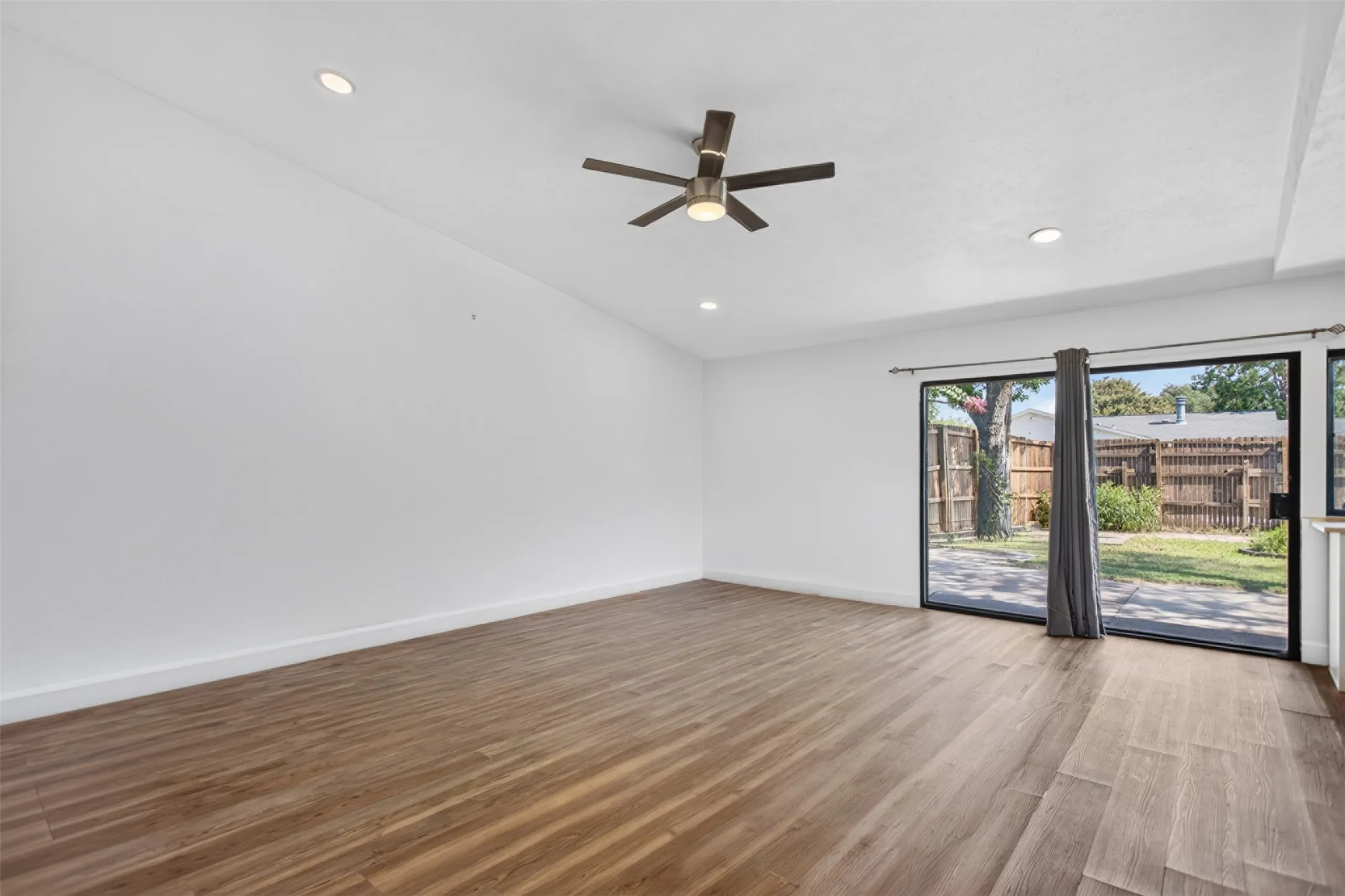 Living Room with Ceiling fan and Luxury Vinyl Flooring. Large sliding glass window to backyard