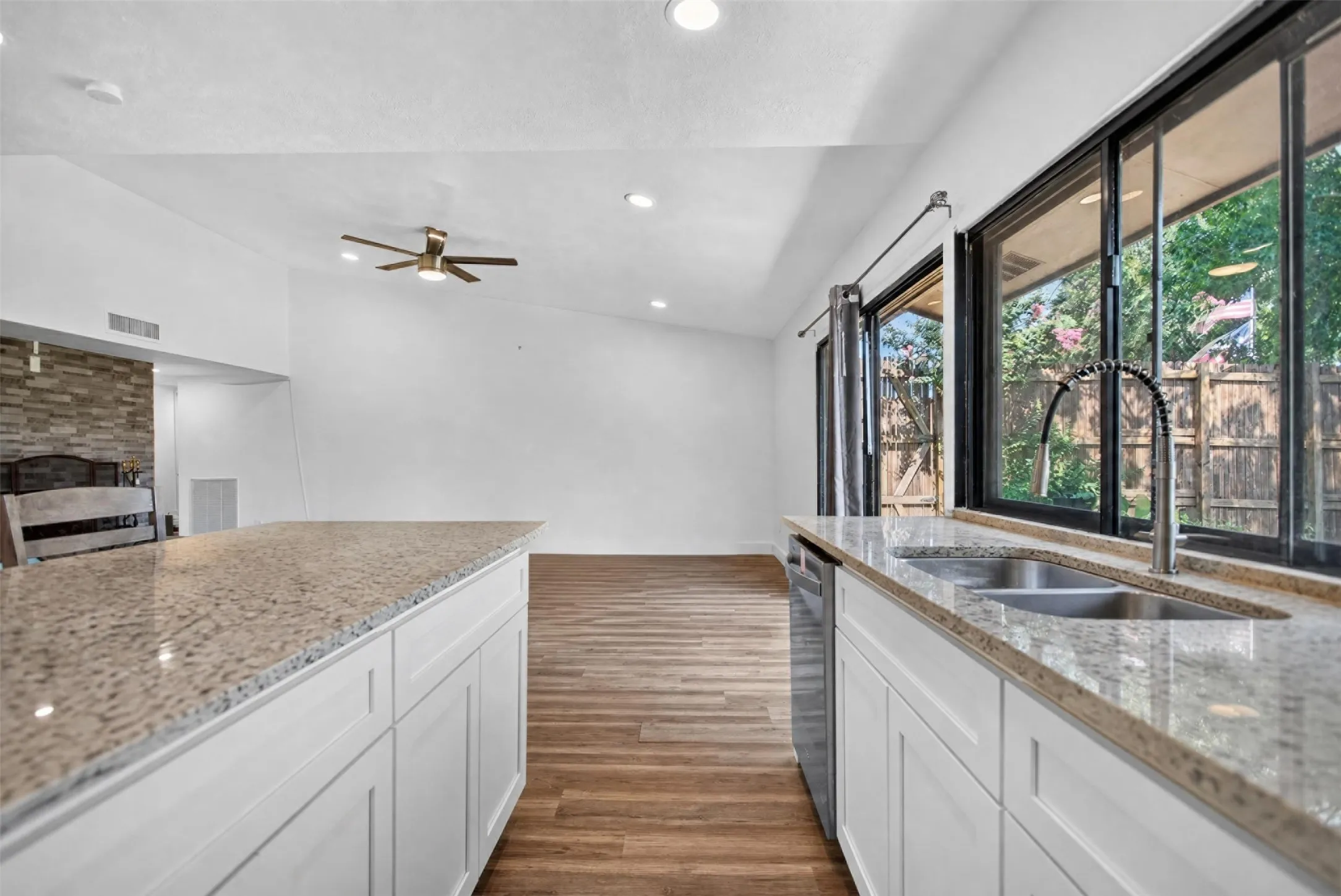 Kitchen featuring stone-finish countertops, white cabinetry, a dual basin stainless steel sink, and a built-in stainless steel dishwasher