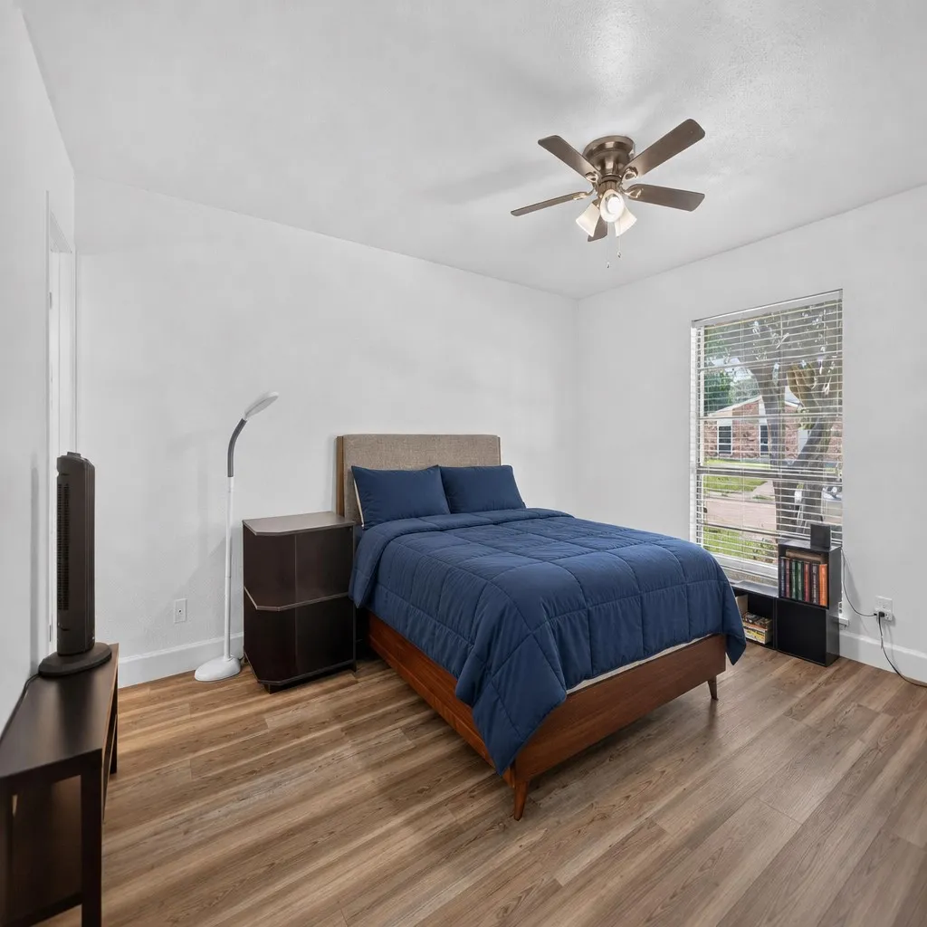 Bright bedroom Staged featuring wood-finish flooring and a ceiling fan with integrated lighting