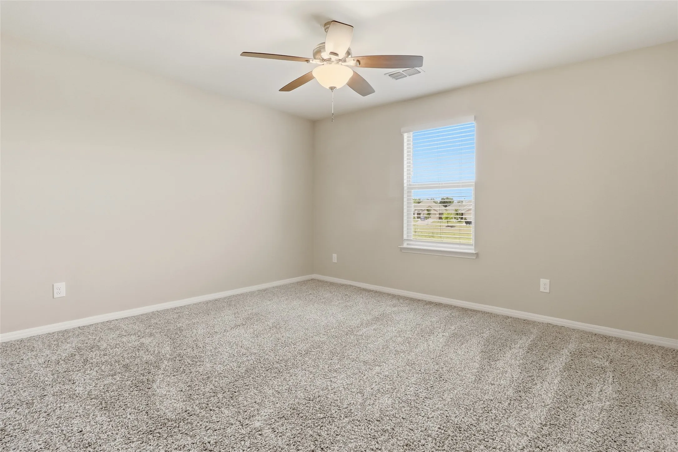 Room featuring neutral wall paint, gray textured carpet, and a window with horizontal blinds
