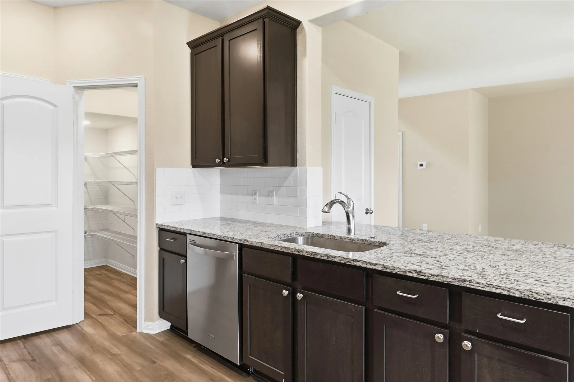 Kitchen island featuring a stainless steel sink, granite-style countertop, and dark wood cabinetry