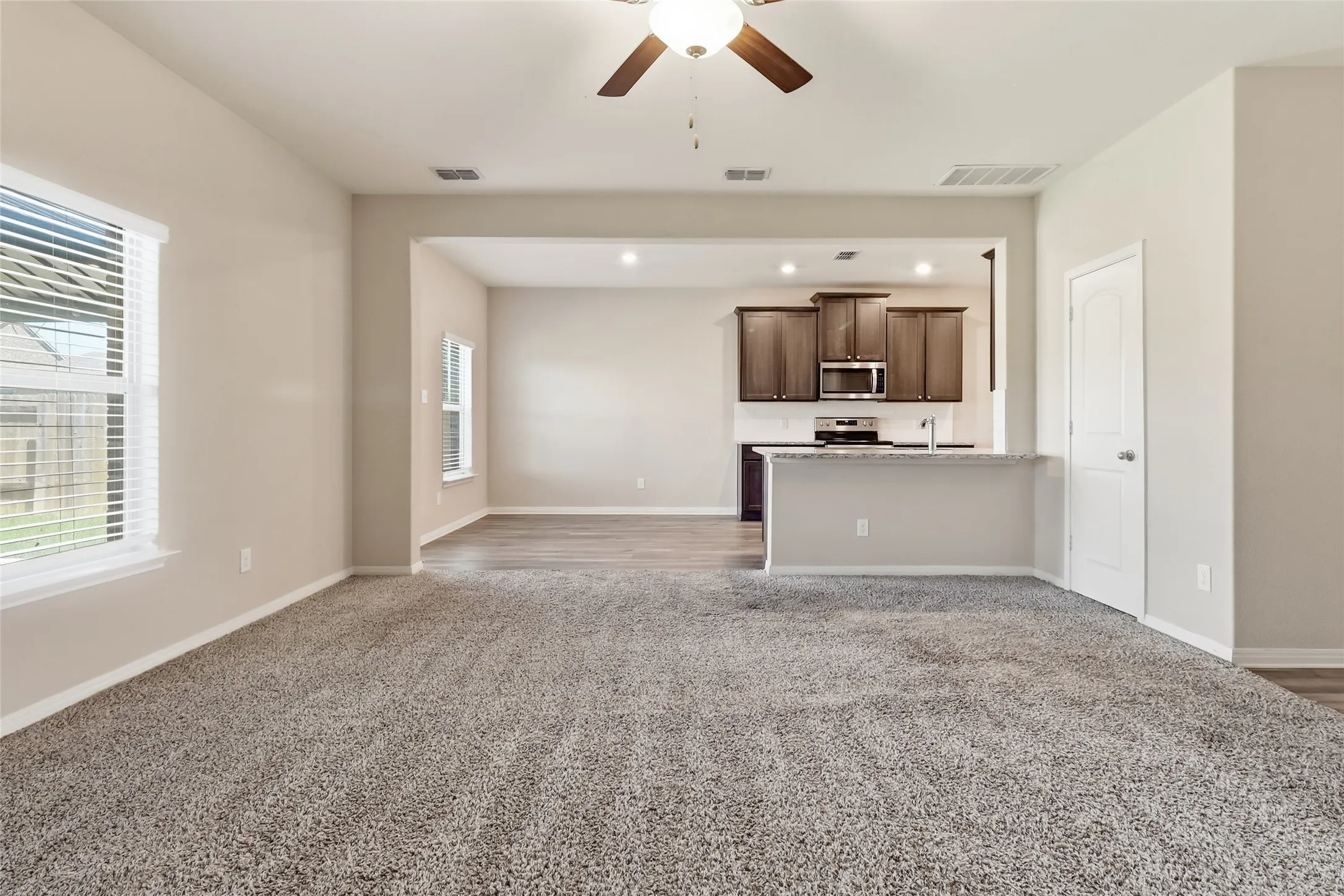 Open-concept living area featuring neutral walls and textured carpeting