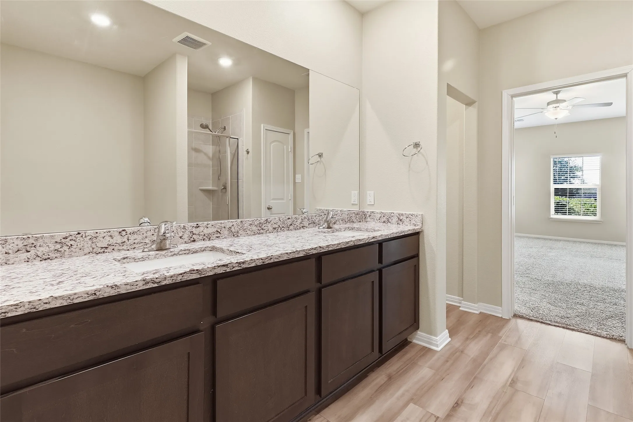 Bathroom featuring a dual vanity with a light-colored countertop and dark wood-finish cabinetry