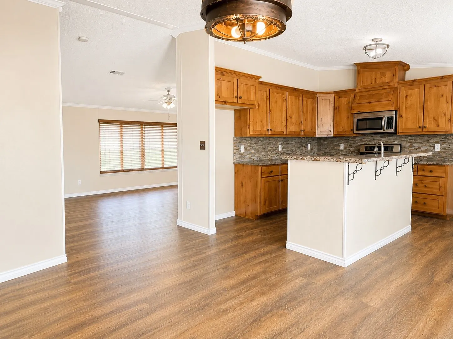 Kitchen featuring wood cabinetry, granite countertops with a stone tile backsplash, and a stainless steel microwave