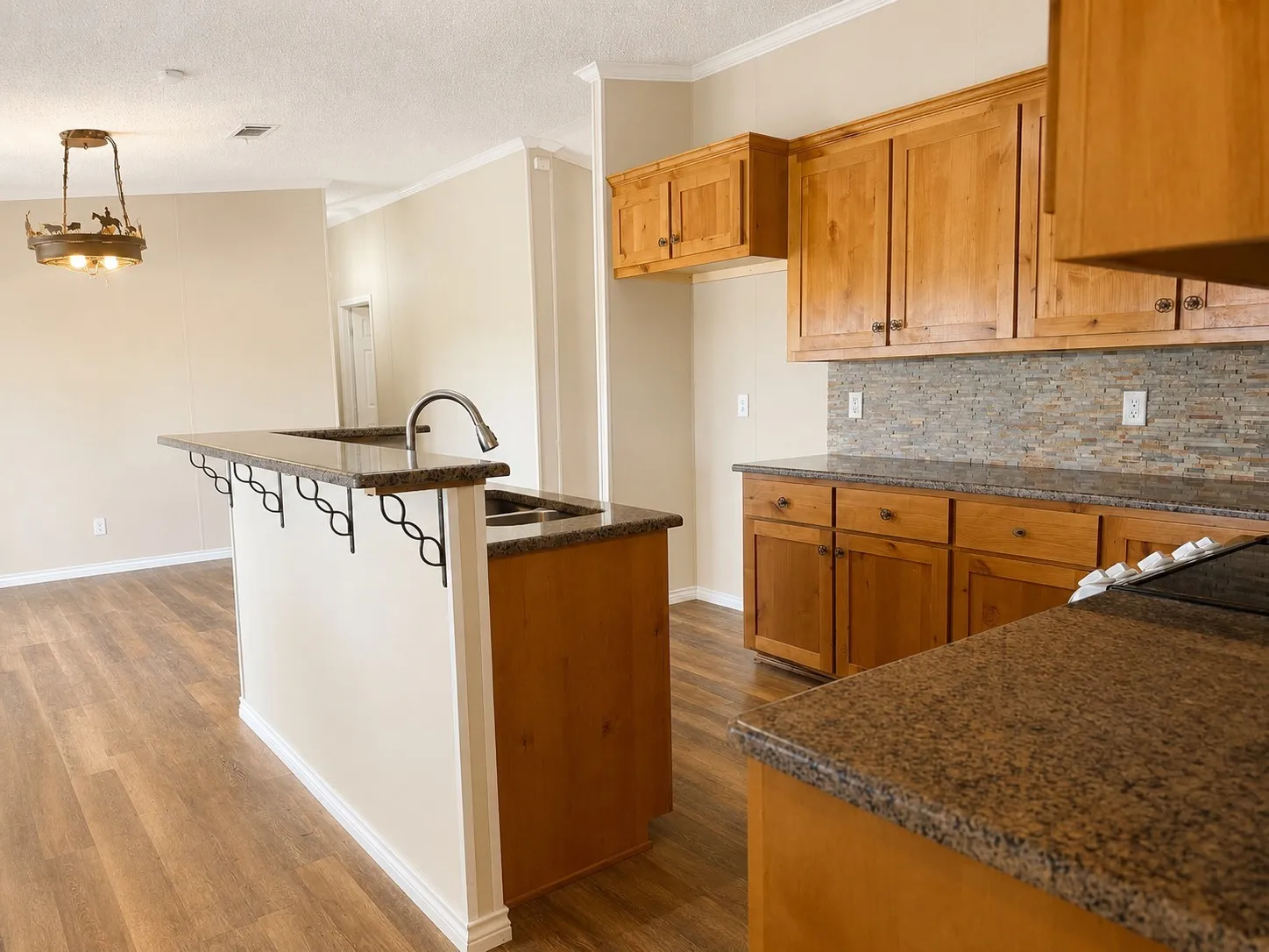 Kitchen area featuring wood-finish flooring, granite countertops, wood cabinetry, and a mosaic tile backsplash