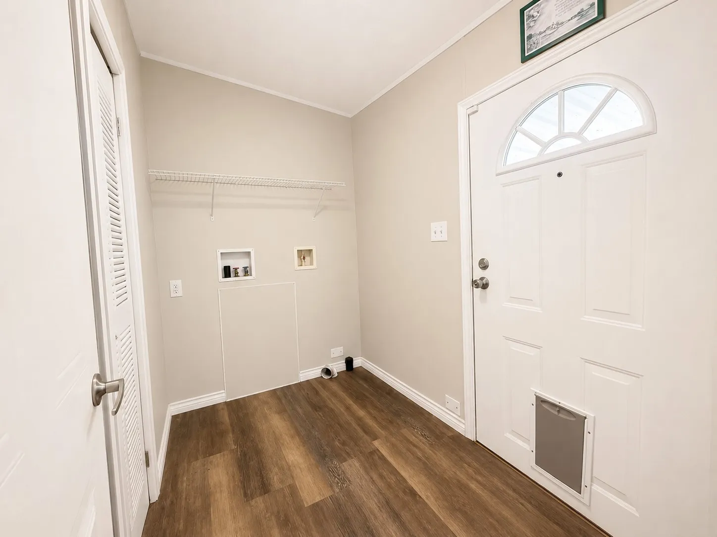 Dedicated laundry area featuring wood-finish flooring, light neutral wall tones, and a wall-mounted wire shelf