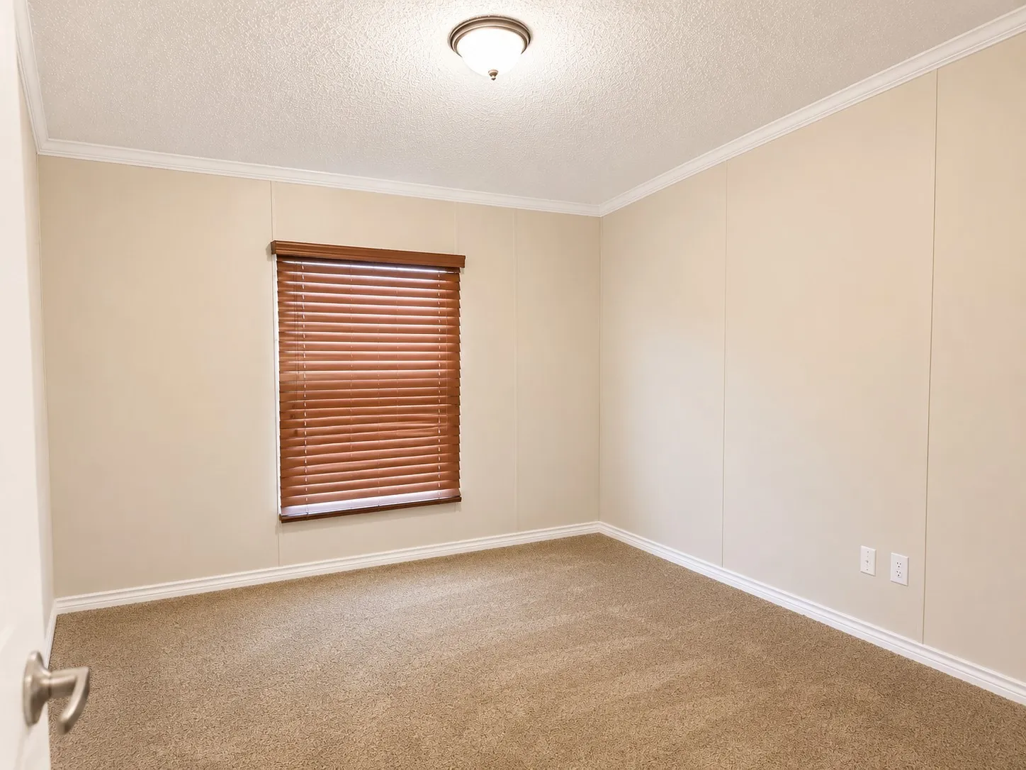 Neutral-toned room featuring a single window with wood-look blinds, textured ceiling, and crown molding