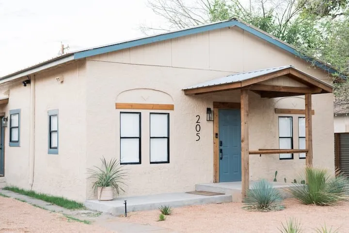 Stucco exterior featuring a covered entry with a metal roof and exposed wood beams