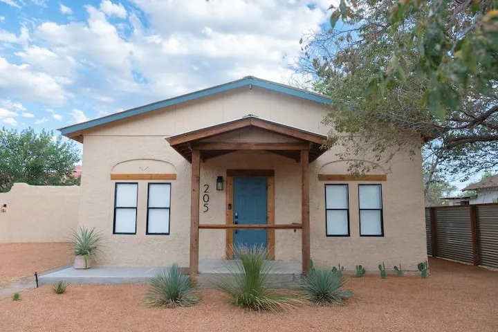 Stucco exterior featuring a covered entry with wood posts and a blue front door