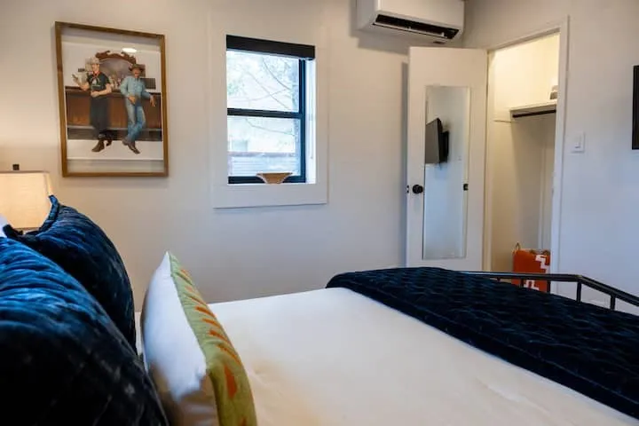 Bedroom featuring a window with black trim, a mini-split AC unit, and a built-in closet with shelving