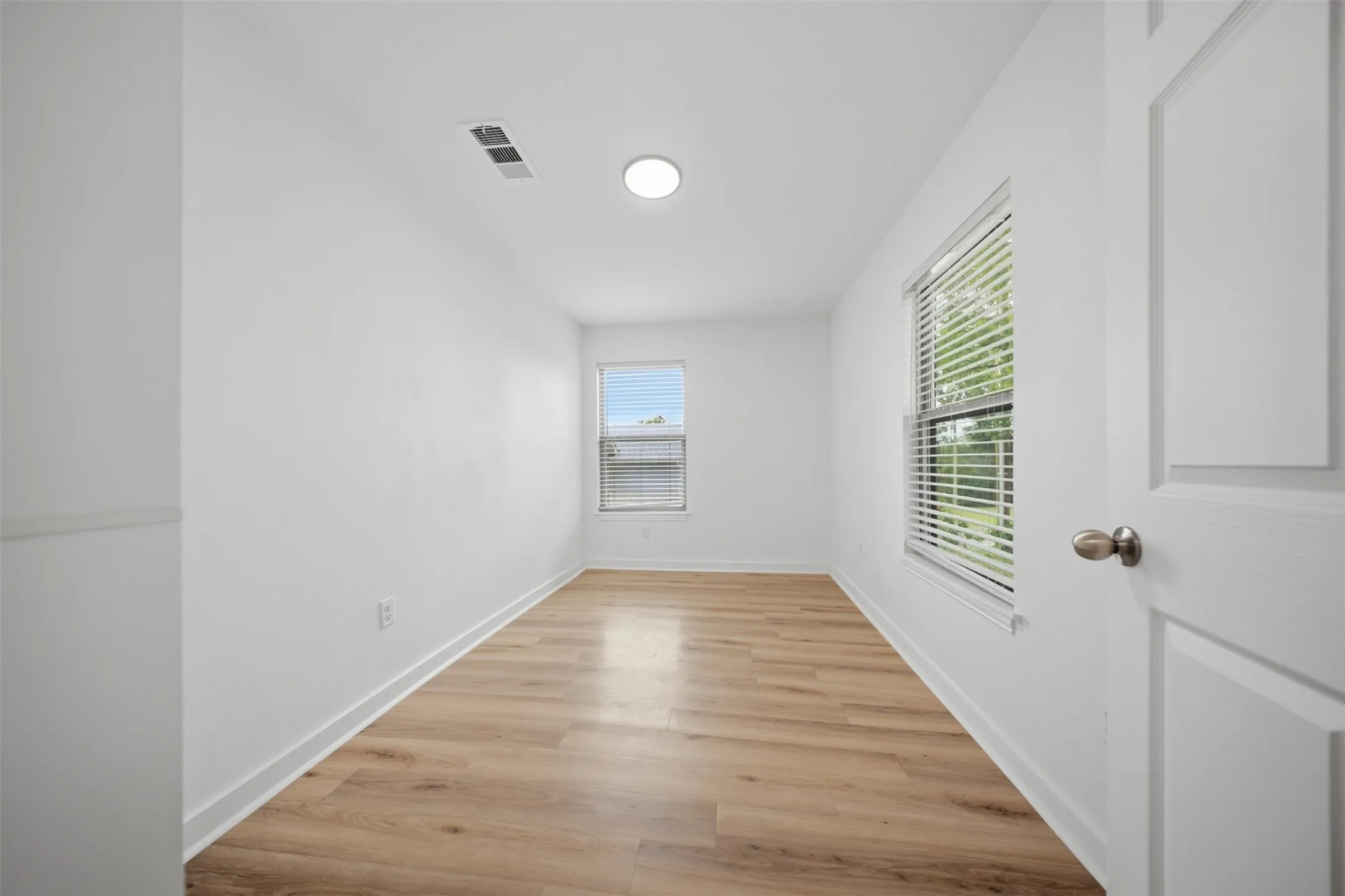 Interior room featuring light wood-finish flooring, white walls, and a recessed ceiling light