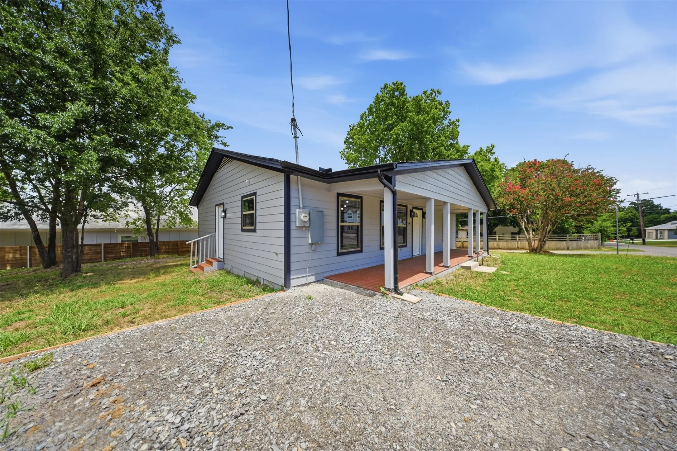 Single-story residence featuring light gray siding, black trim, and a covered front porch with white columns