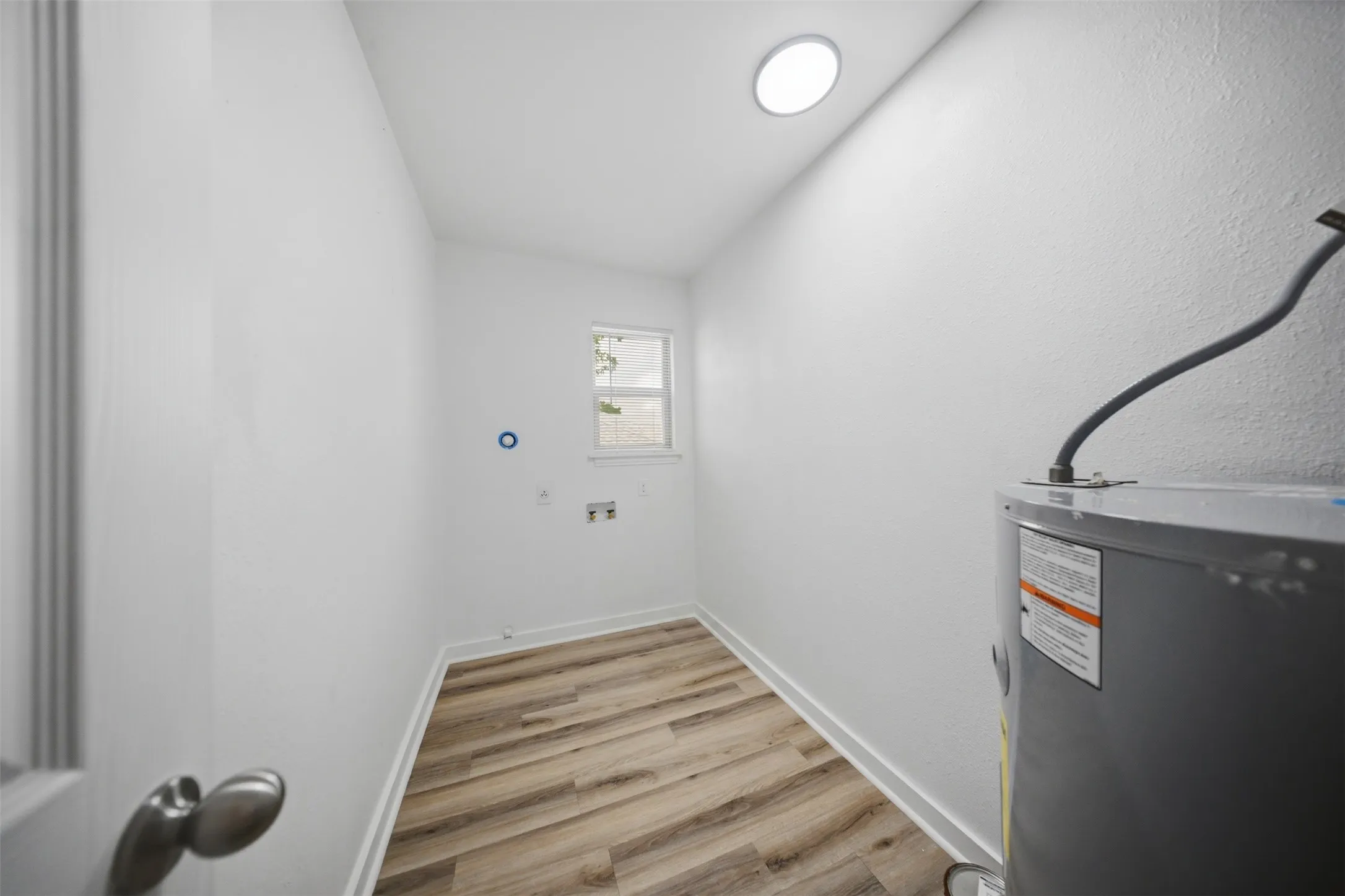 Utility space featuring light wood-finish flooring, a window, and recessed ceiling lighting