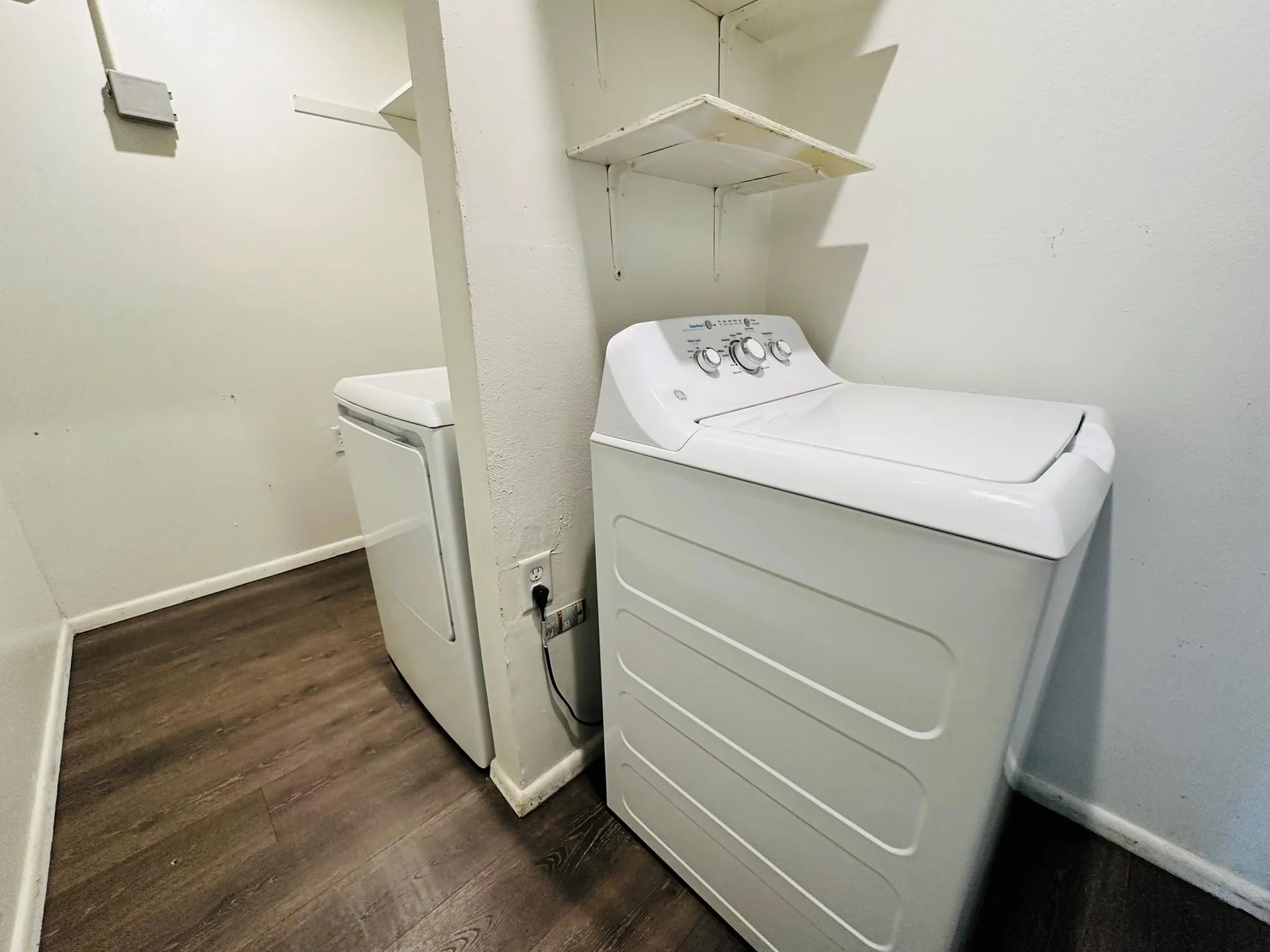 Laundry area featuring wood-finish flooring and built-in shelving
