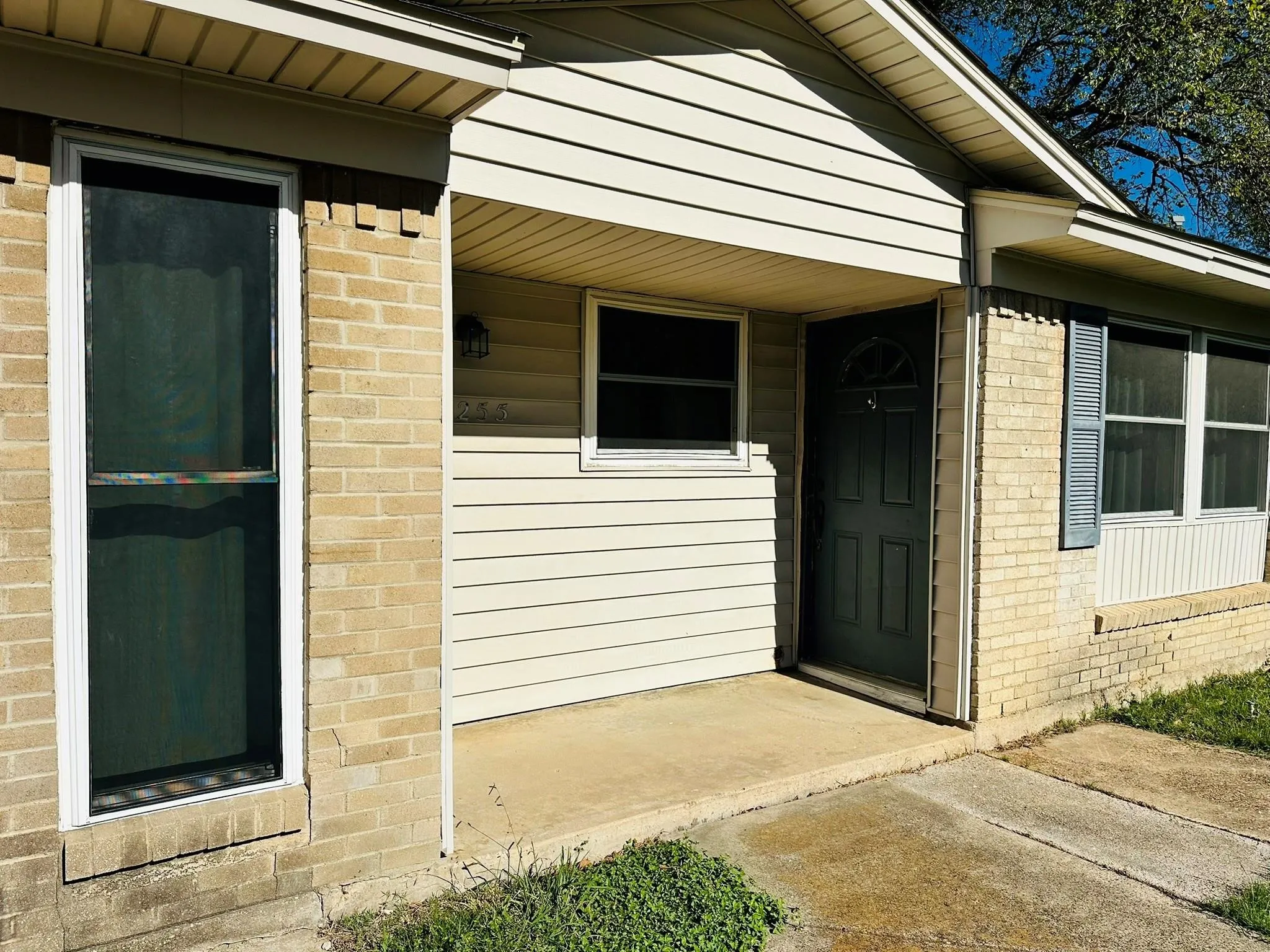 Front exterior featuring a covered entry porch, brick facade, horizontal siding, and multiple windows with shutters