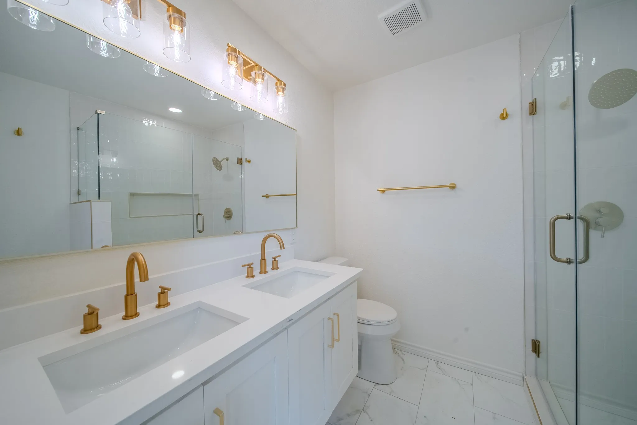 Dual vanity featuring integrated rectangular sinks and brass-finish hardware