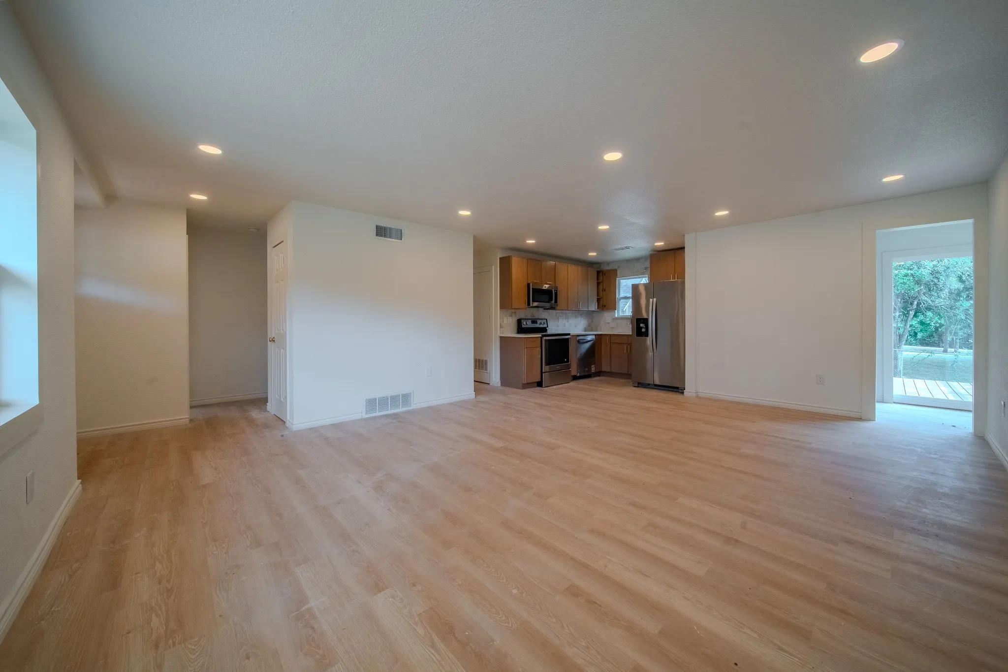 Open-concept interior featuring wood-finish flooring, recessed lighting, and a kitchen with stainless steel appliances and wood cabinetry