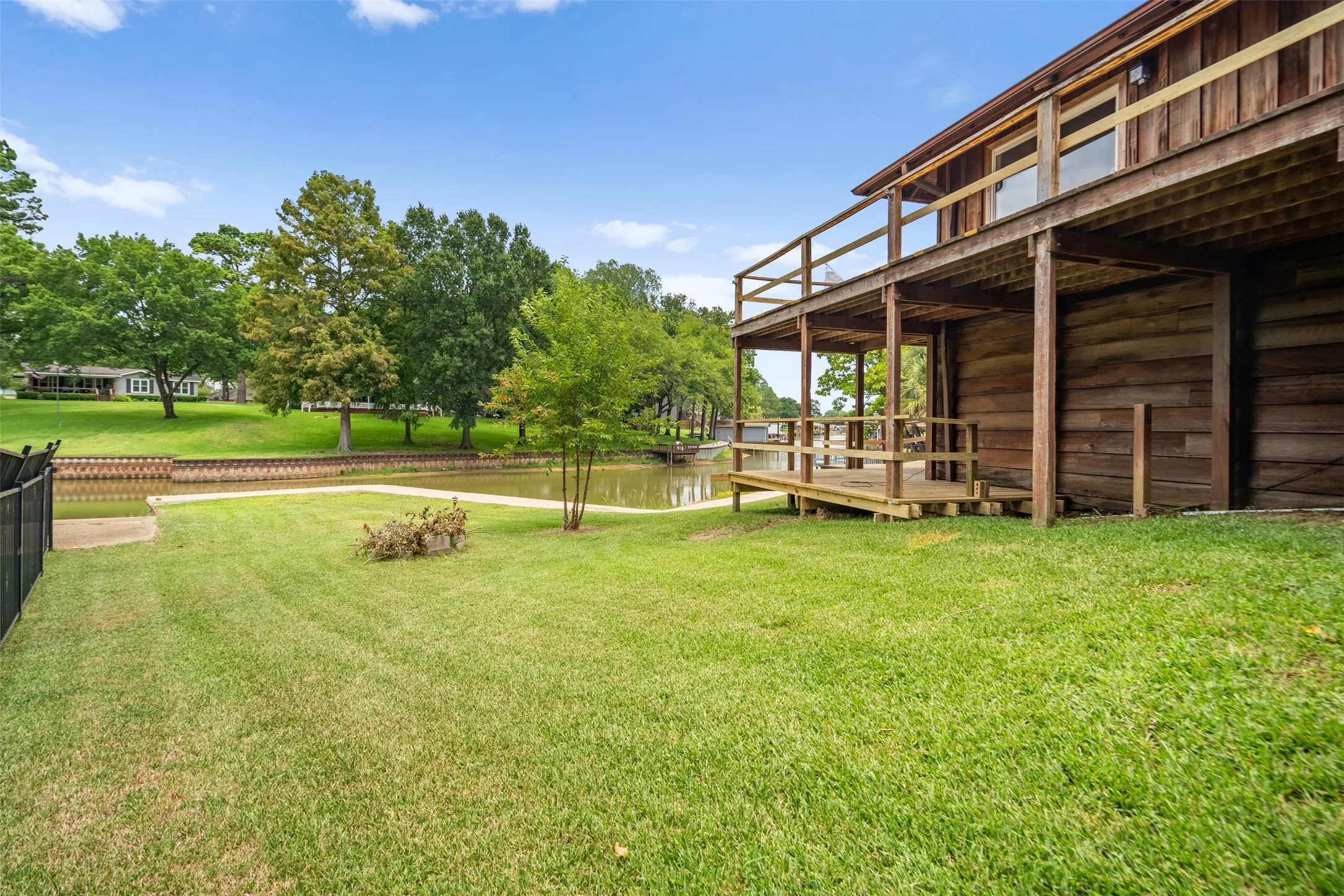 Expansive waterfront property featuring a two-story wood-sided structure with a double-level deck