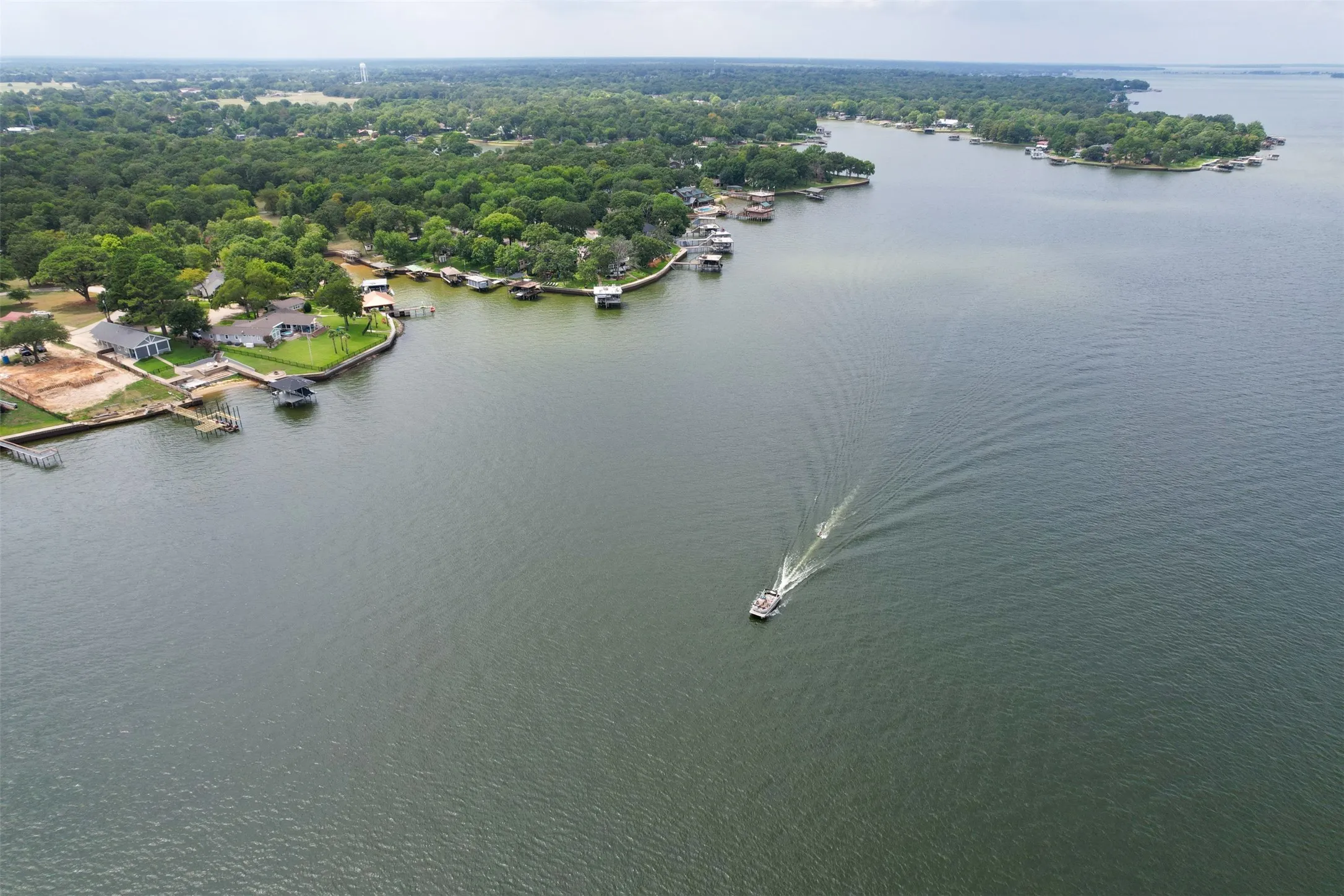 Expansive waterfront property featuring a manicured lawn, multiple boat docks, and direct access to the lake