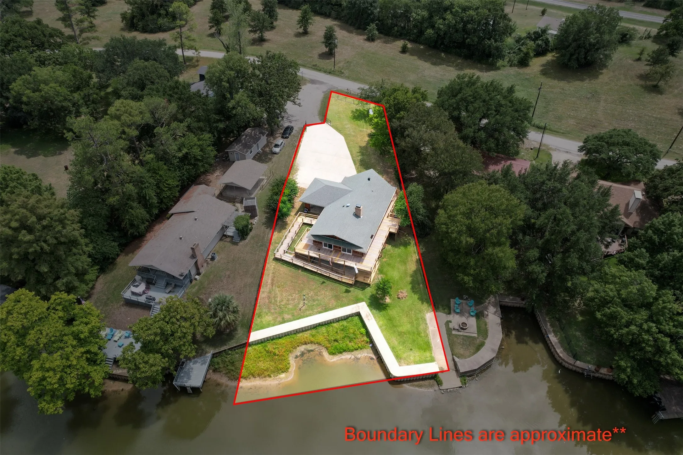 Waterfront property featuring a main residence with an expansive elevated deck, an additional structure, and a private dock