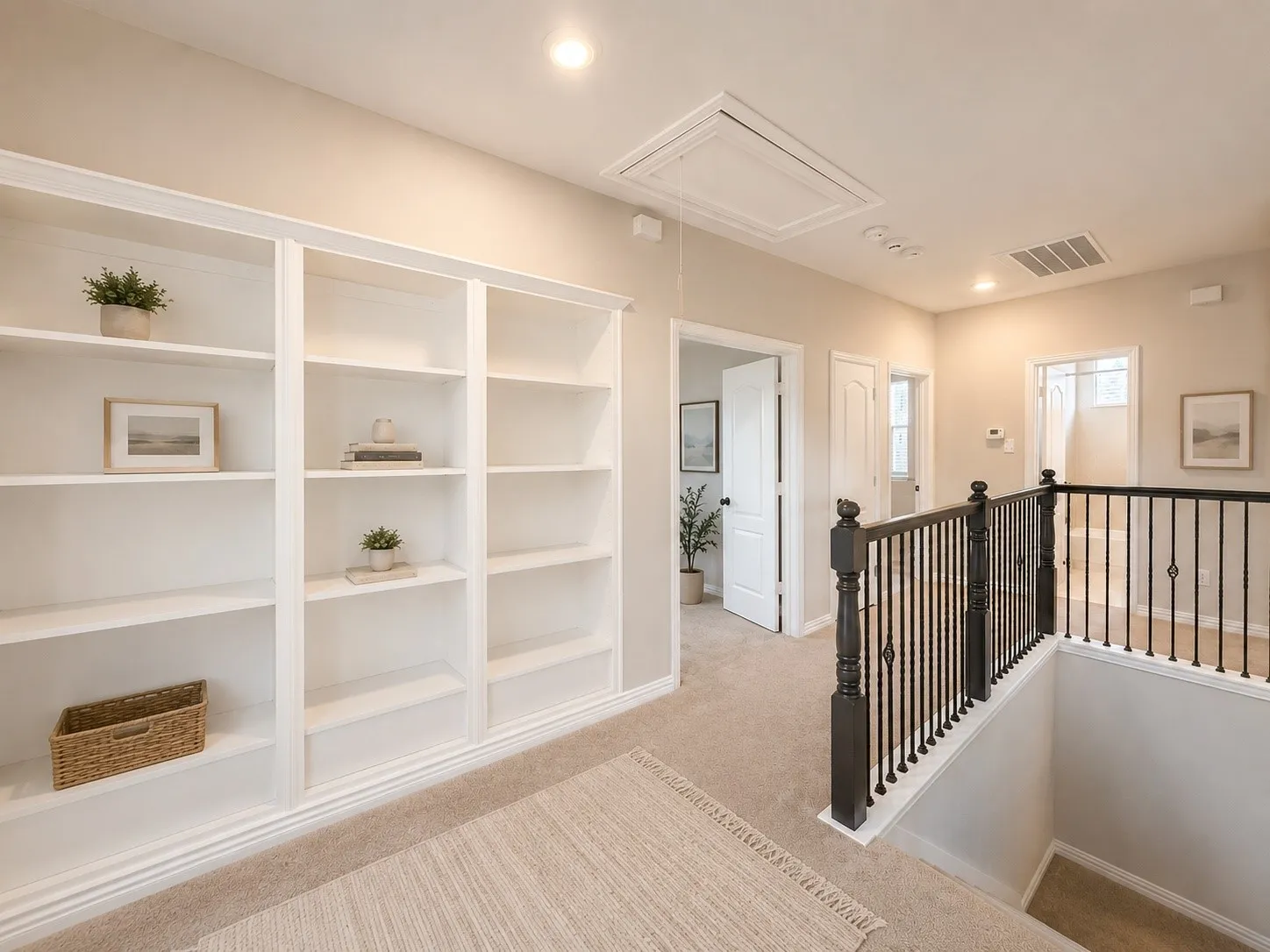 Built-in white shelving unit with crown molding, recessed lighting, carpeted flooring, and dark wood newel post with black metal balusters