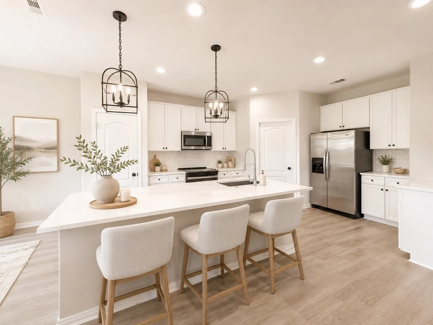 Spacious kitchen featuring a large island with seating, stainless steel appliances, white cabinetry, and wood-finish flooring