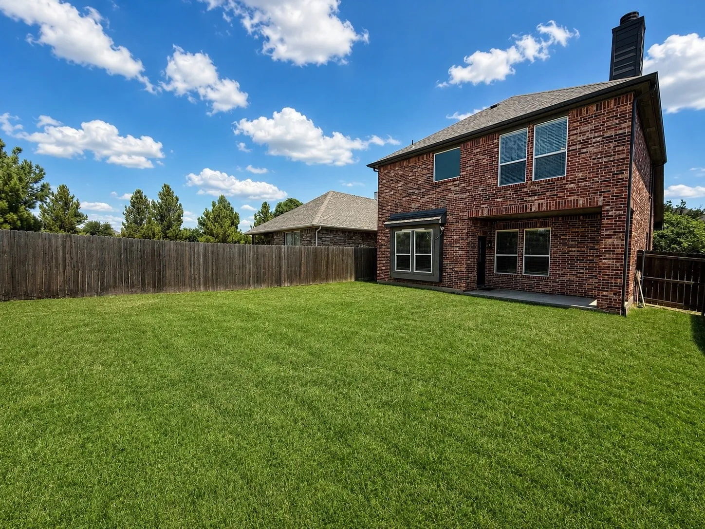 Expansive green lawn with a full privacy fence