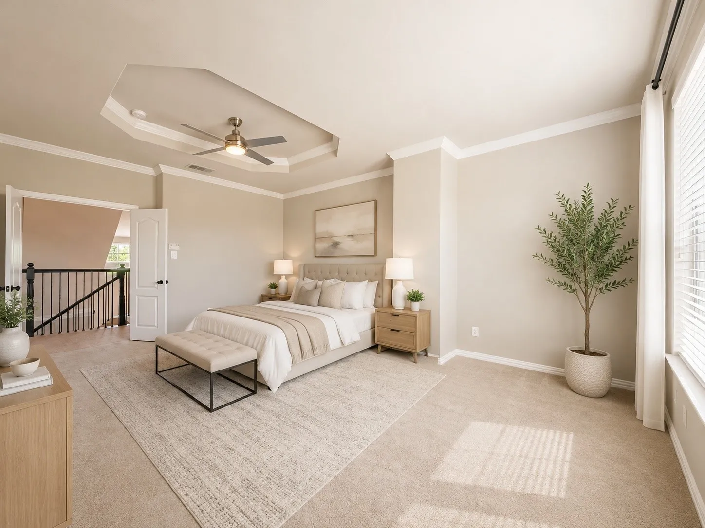 Spacious bedroom featuring neutral carpeting, tray ceiling with fan, crown molding, and large windows with blinds