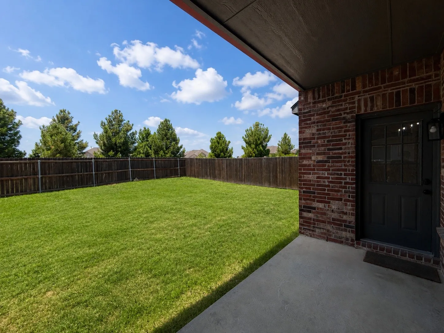 Expansive green lawn surrounded by a wooden privacy fence