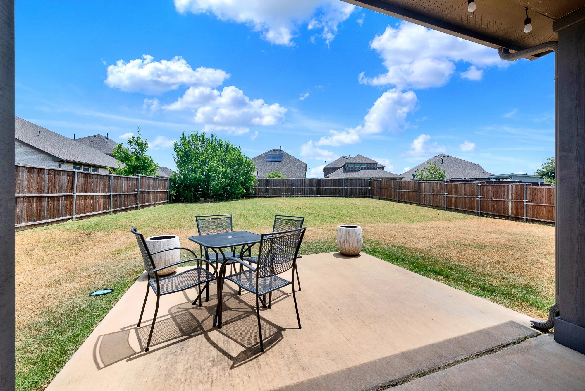 Spacious backyard featuring a concrete patio, wood privacy fencing, and ample green space