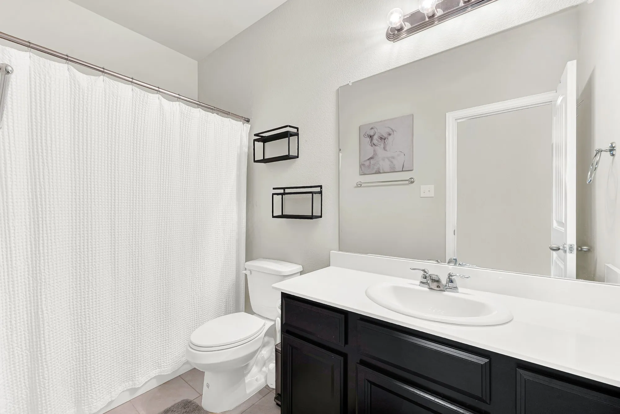 Bathroom featuring a dark wood vanity with a white countertop, an undermount sink with a chrome faucet, a large mirror, and a toilet