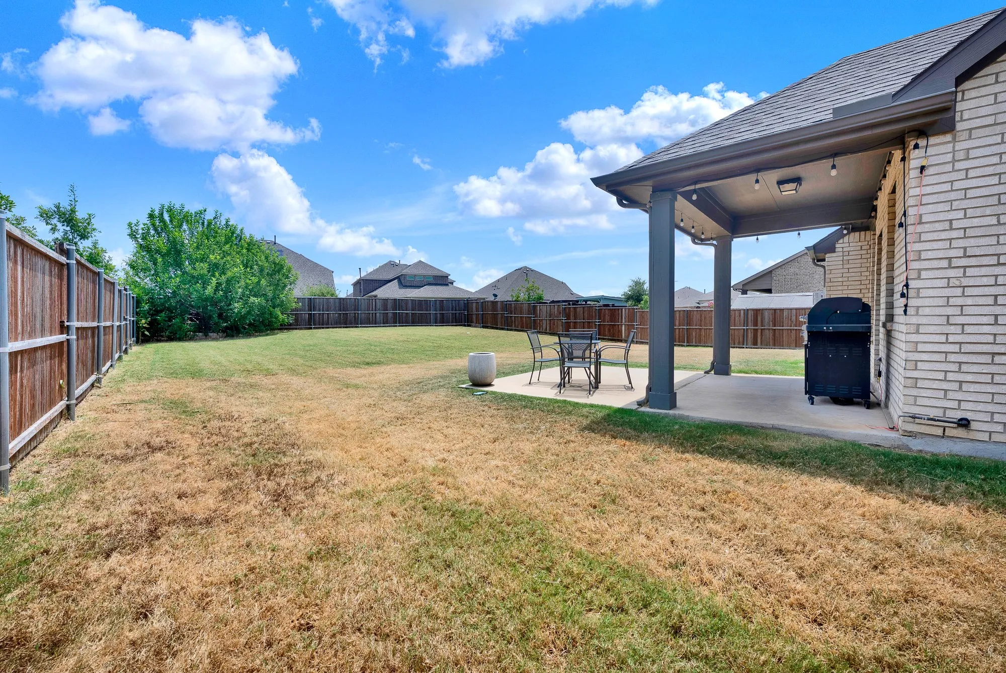 Expansive backyard with a covered patio featuring recessed lighting and string lights