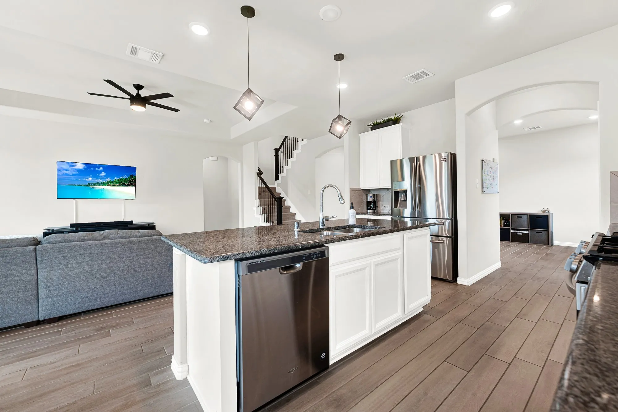 Kitchen island featuring granite countertops, a built-in stainless steel dishwasher, and a stainless steel sink with a gooseneck faucet