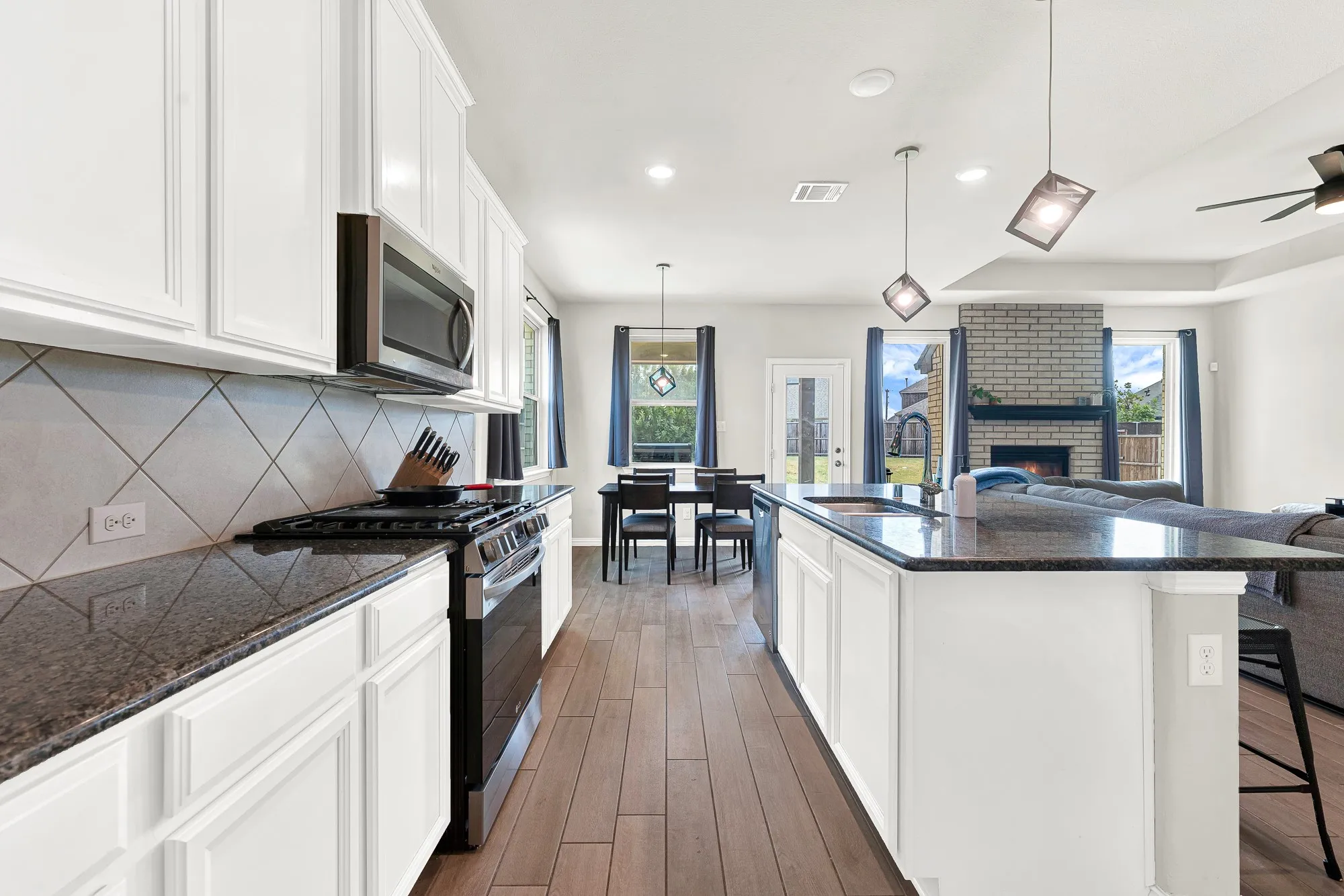 Kitchen featuring white cabinetry, dark stone countertops, stainless steel appliances, and a diagonal tile backsplash