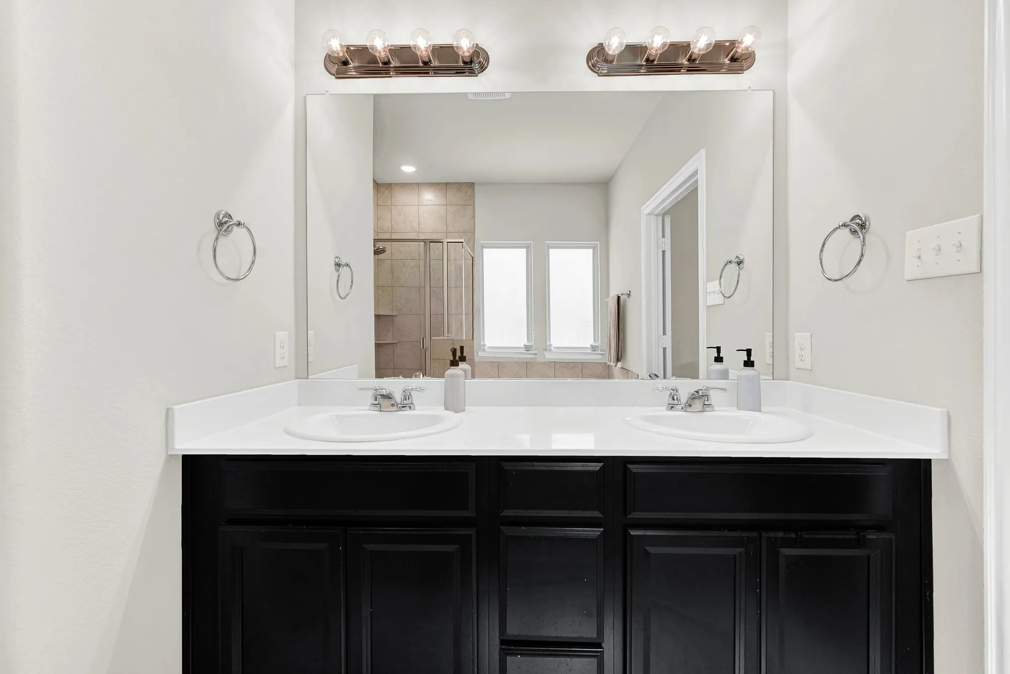 Double vanity with two integrated sinks, a white countertop, and dark cabinetry