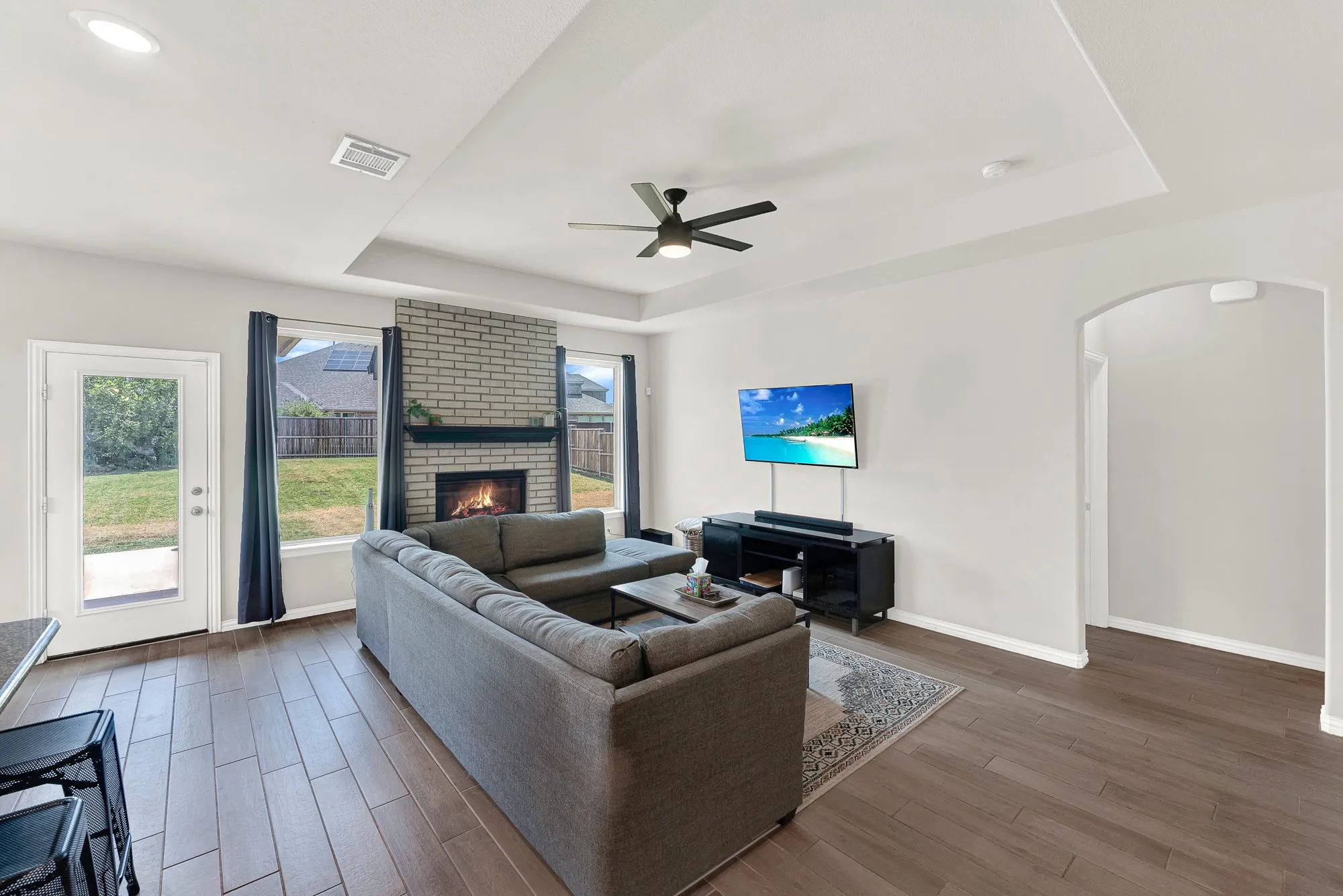Spacious living area featuring wood-finish flooring, a tray ceiling, and recessed lighting