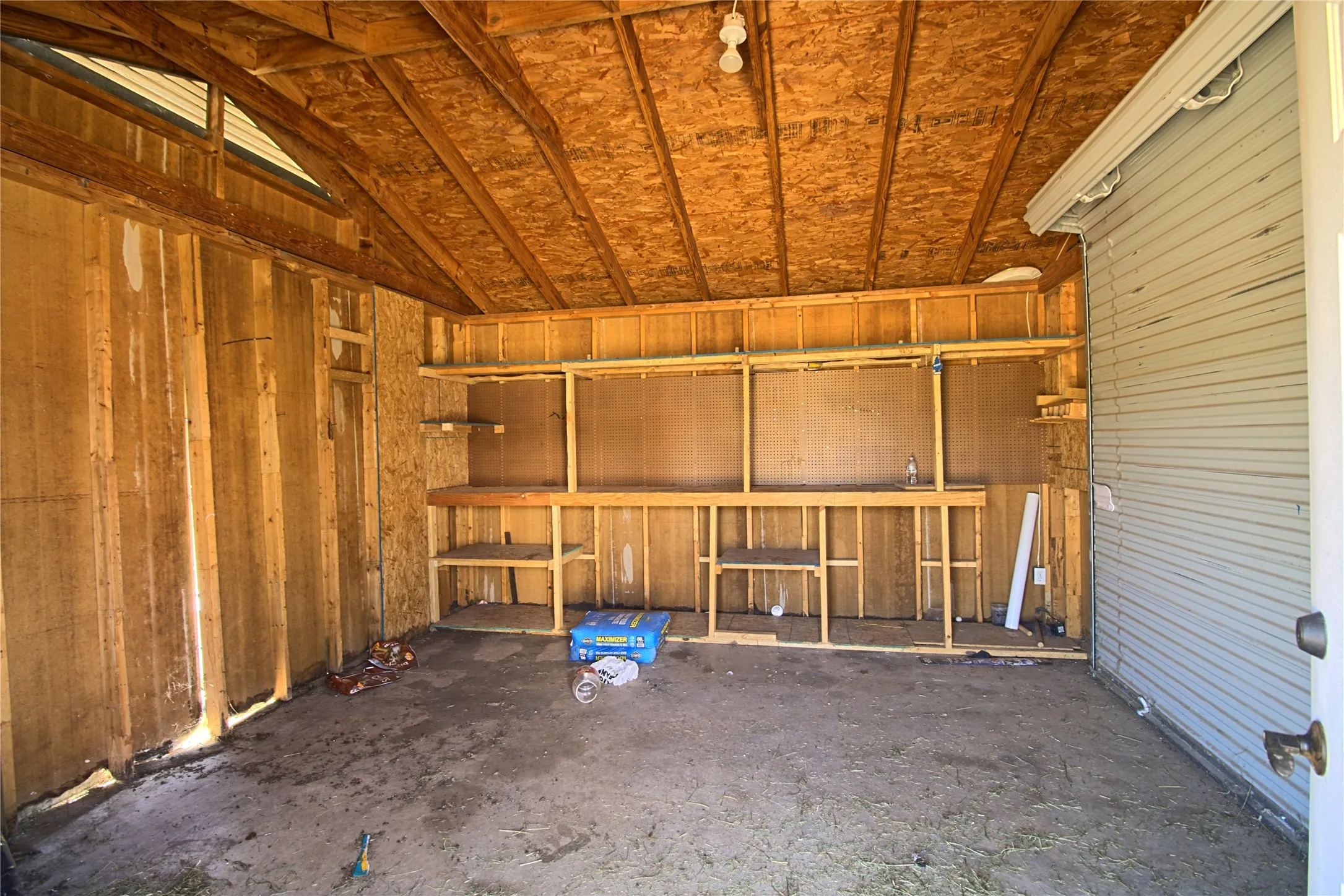 Utility structure with exposed wood framing, a sloped ceiling, and built-in shelving