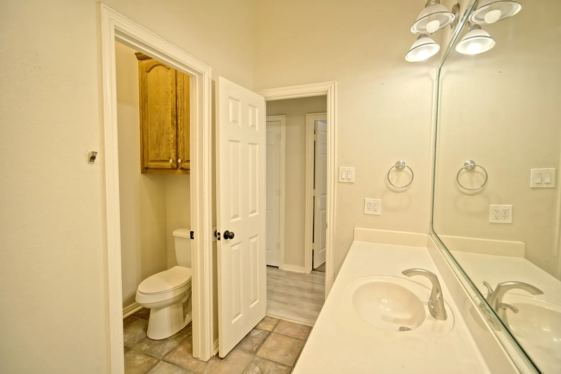 Bathroom featuring a vanity with an integrated sink, a large wall mirror, and a three-bulb light fixture