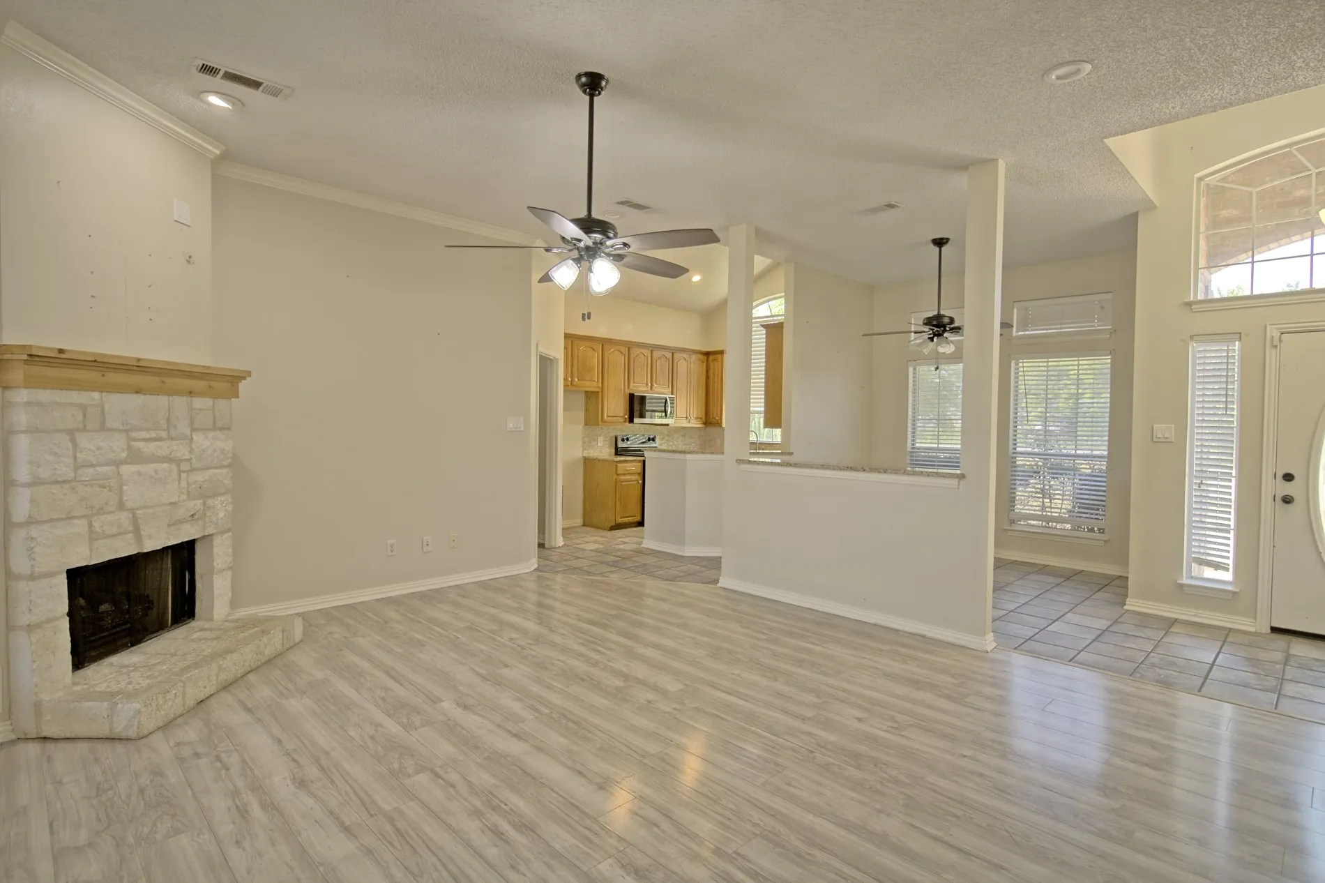 Spacious interior featuring a stone fireplace with a wood mantle, light wood-finish flooring, and recessed lighting