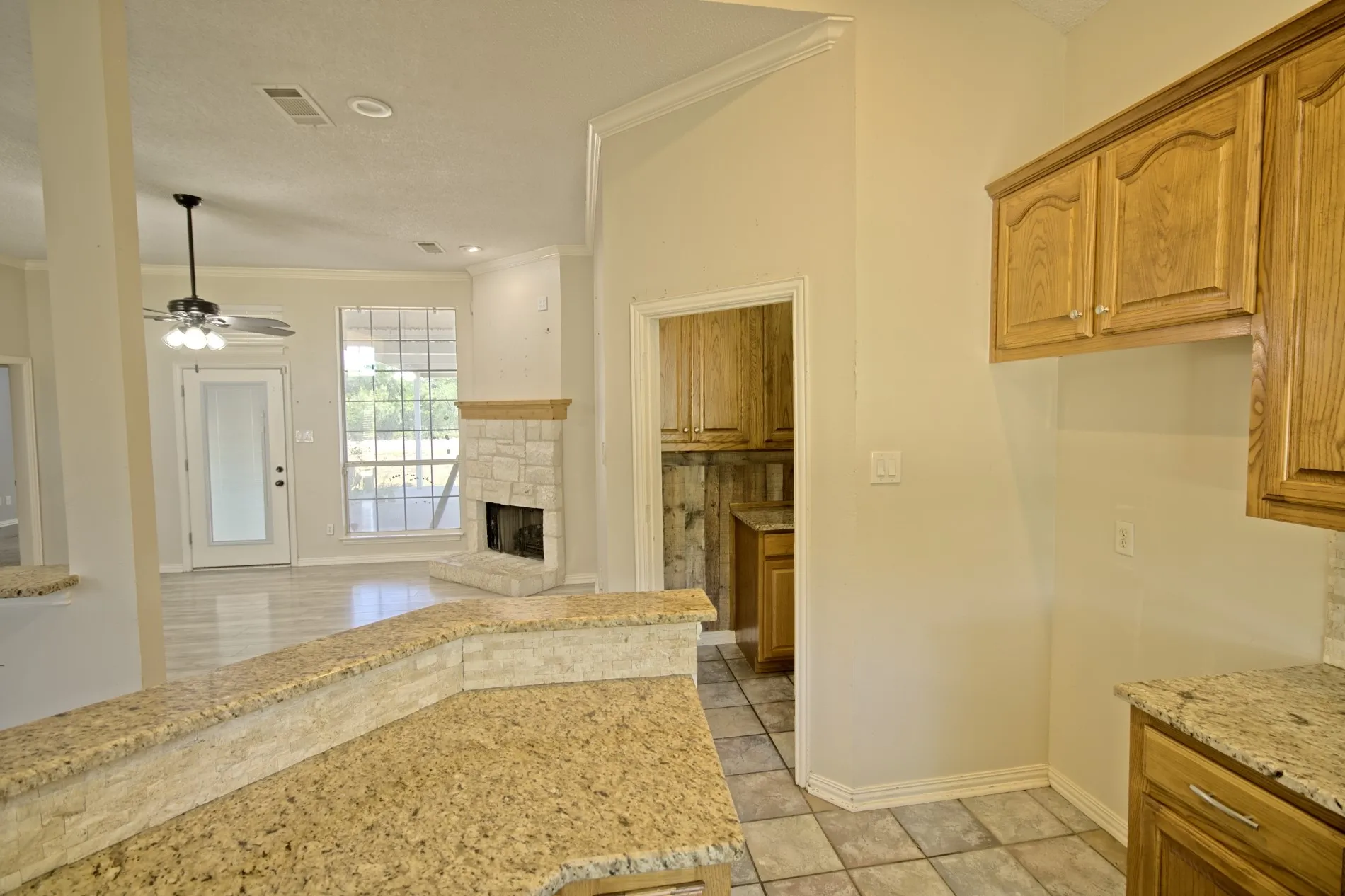 Kitchen features granite countertops, wood cabinetry, and tile flooring