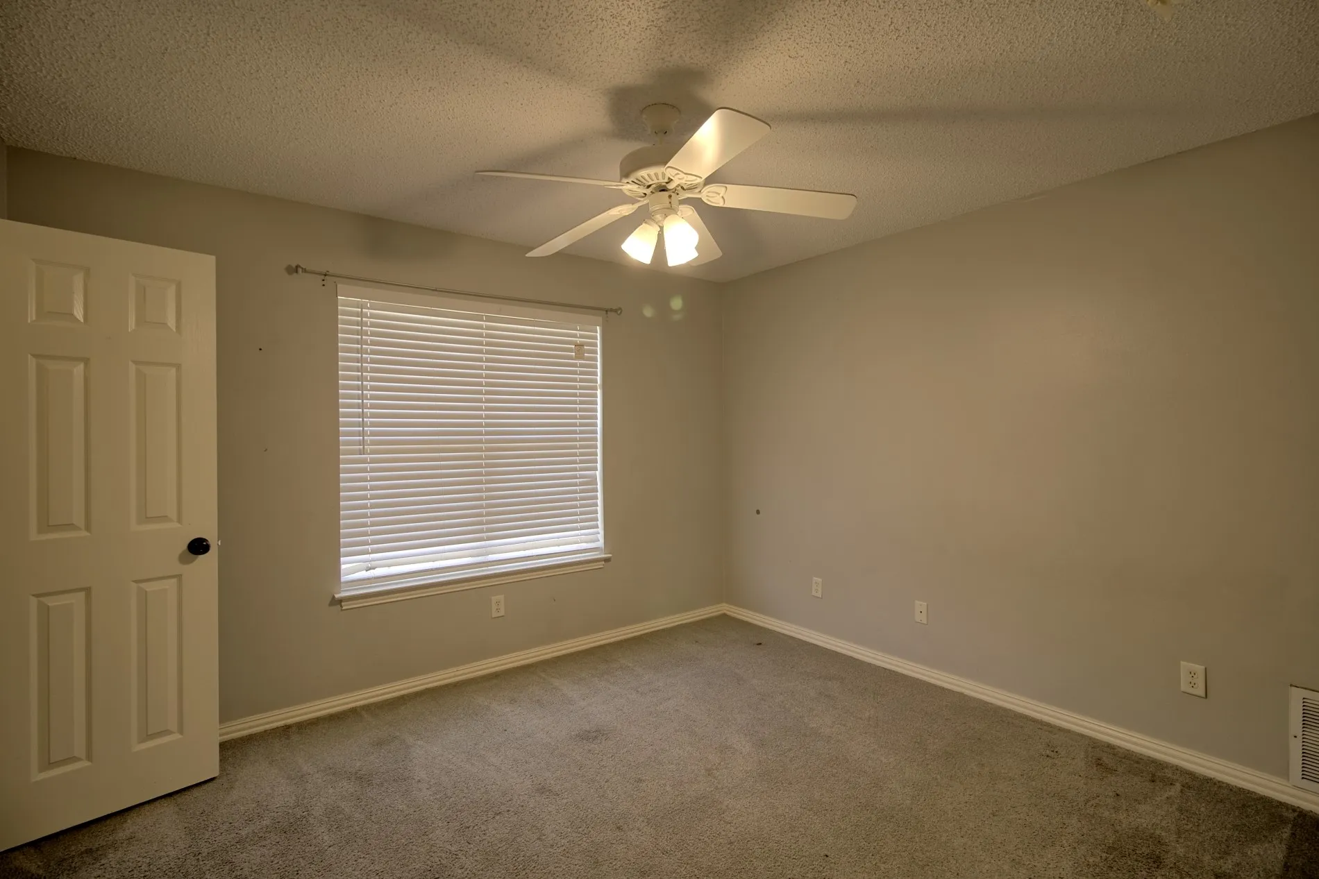 Carpeted room featuring a ceiling fan with integrated lighting, a window with horizontal blinds, a paneled door, and neutral-toned walls
